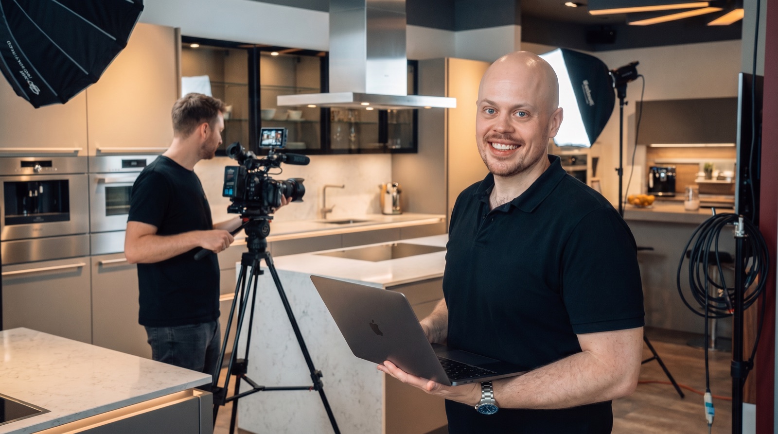 Alex Tauer am MacBook, Kamera im Hintergrund